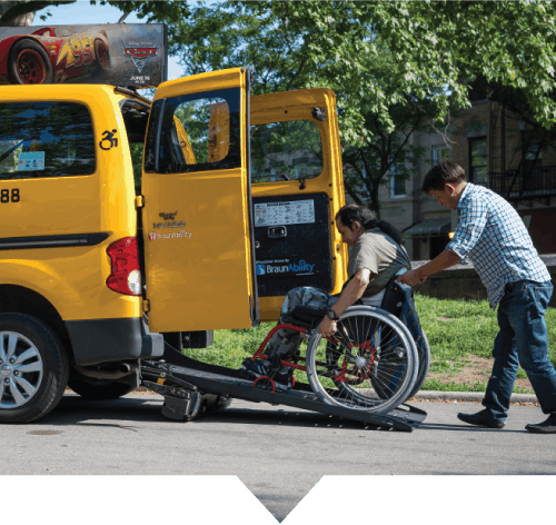 A TLC Accessible Dispatch driver helps a man who utilizes a wheelchair into his accessible taxi.
