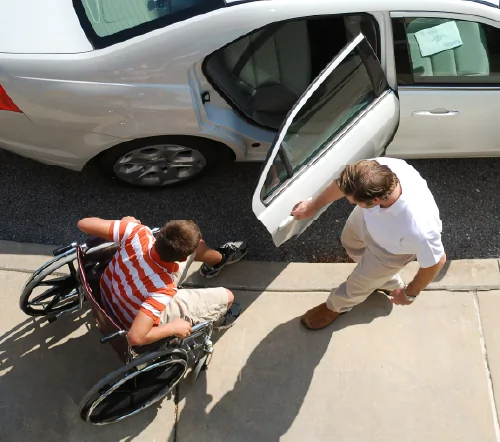 Driver opening up a car door for a passenger in a wheelchair