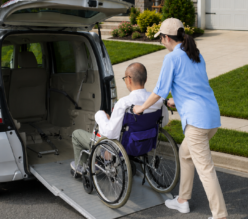 Driver wheeling a passenger up a van ramp