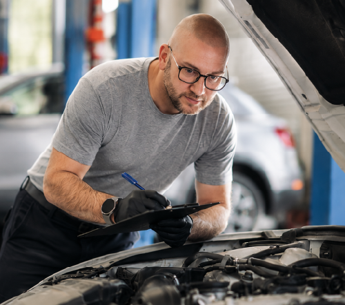 Driver looking under the hood of a vehicle
