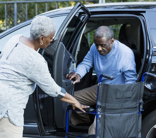 Driver helping senior man out of car and into wheelchair