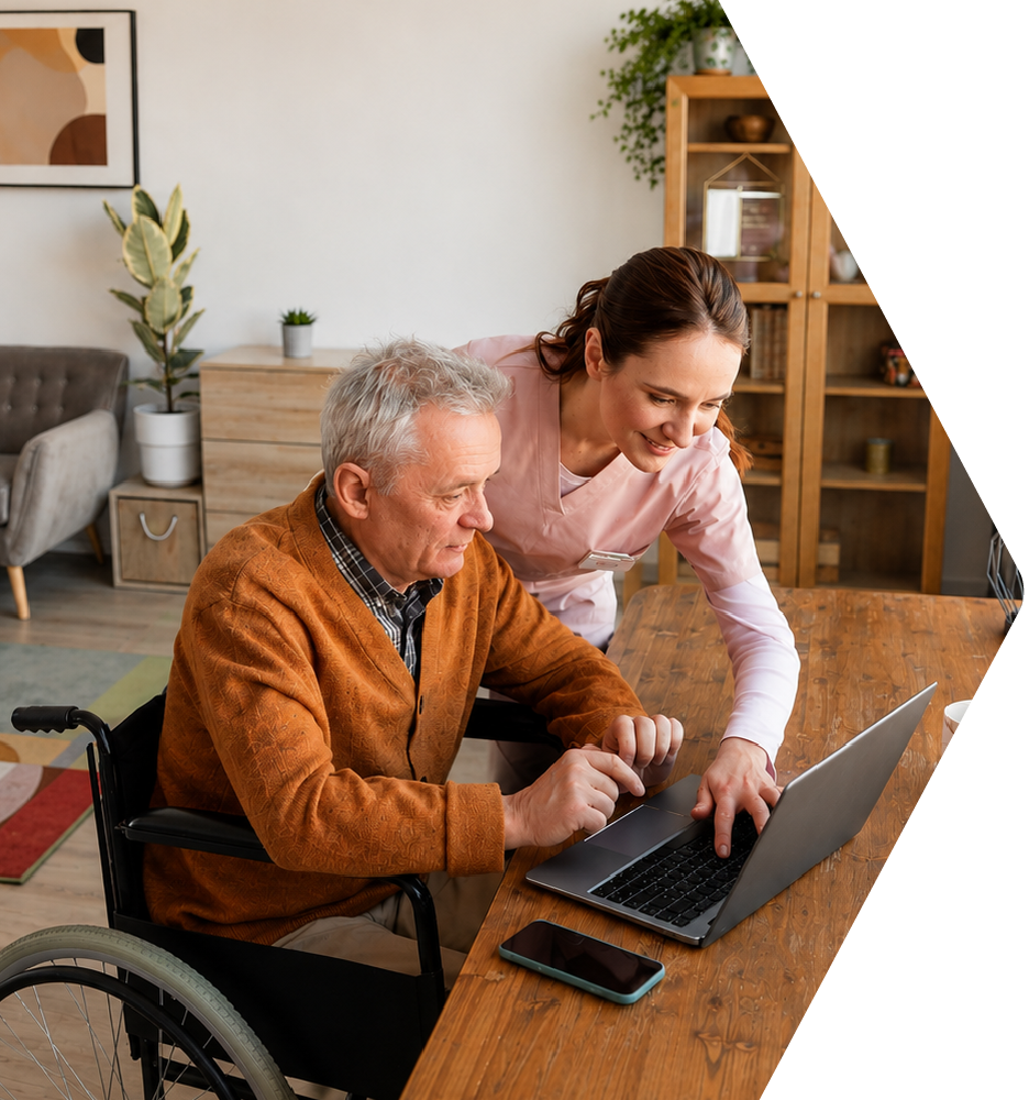 Caretaker helping senior man in a wheelchair with his computer