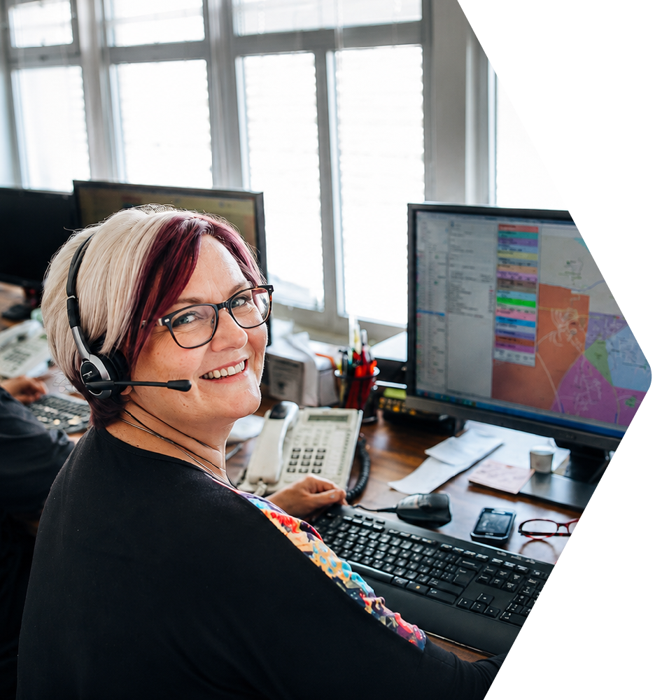 Dispatcher smiling at the camera, sitting in front of a computer monitor